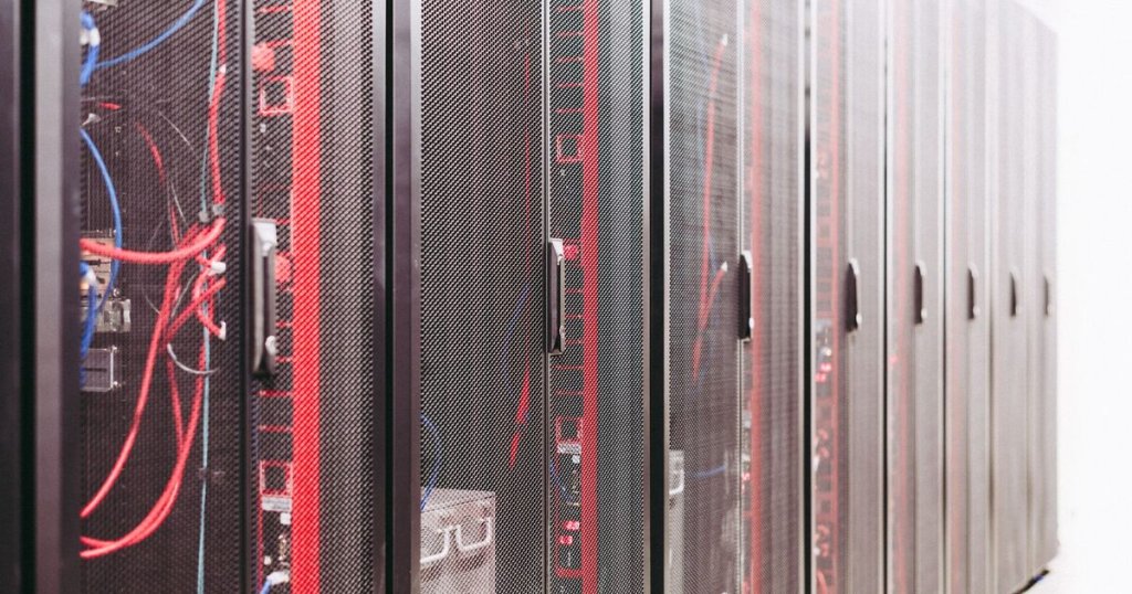 A row of server racks in a data centre with red and blue network cabling