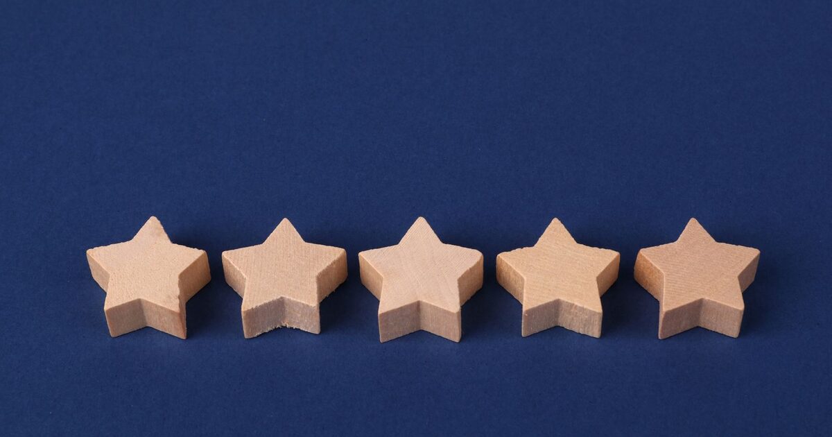 Five wooden stars in a row on a dark blue background, representing a five star product rating