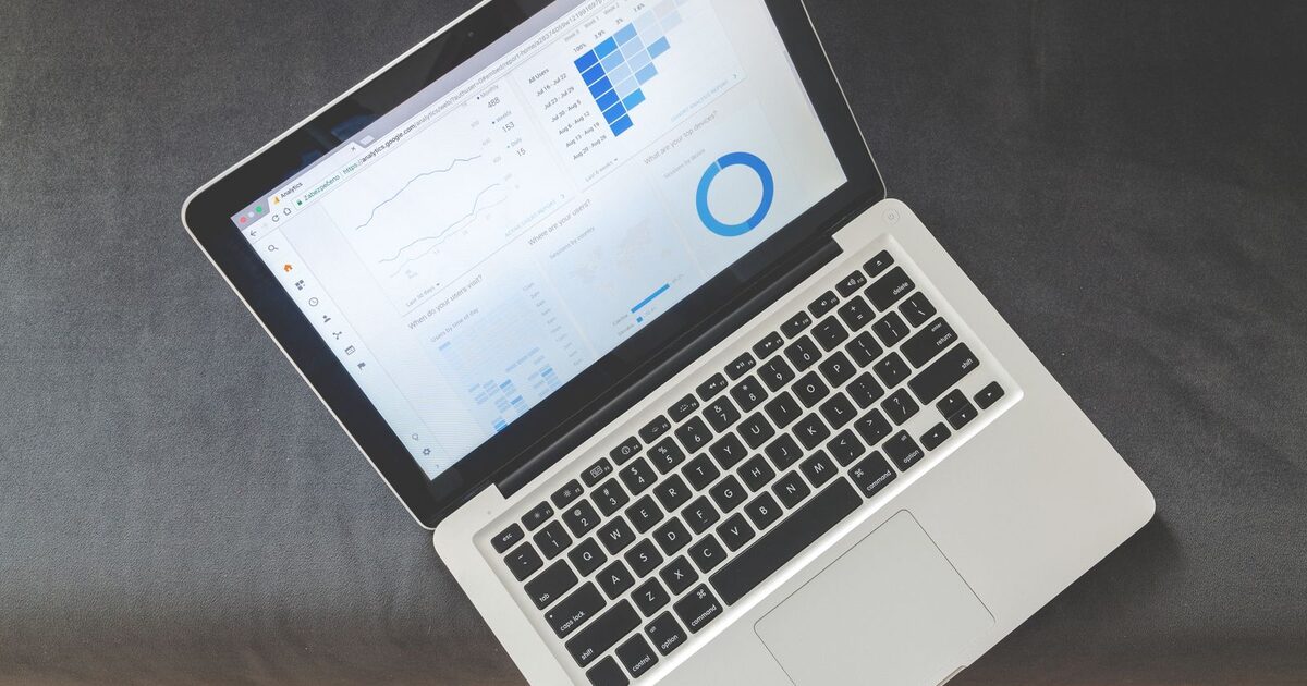 An open laptop on a desk showing a website analytics dashboard with traffic graphs and charts